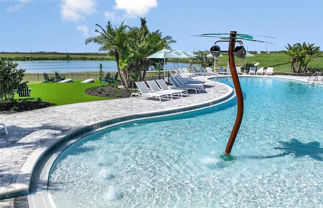 view of swimming pool featuring a water view, a yard, and a patio area