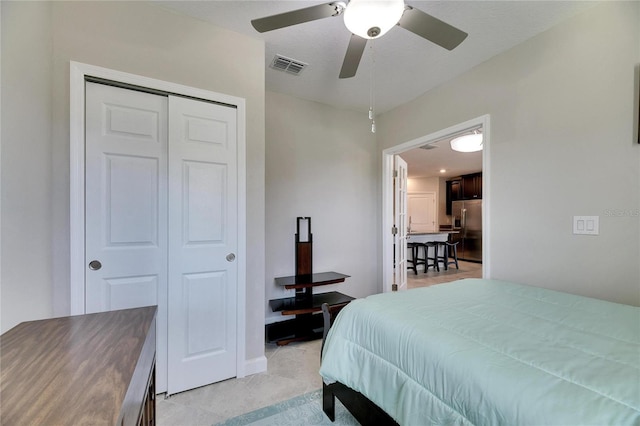 bedroom with ceiling fan, a closet, and stainless steel refrigerator with ice dispenser