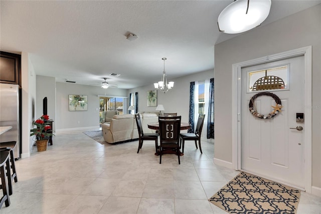 tiled dining space with ceiling fan with notable chandelier, a textured ceiling, and a healthy amount of sunlight