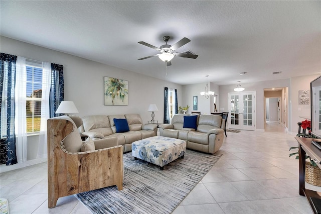 living room featuring ceiling fan with notable chandelier, light tile patterned flooring, and a textured ceiling