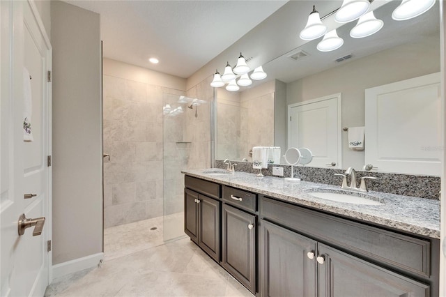 bathroom featuring tile patterned flooring, tiled shower, and vanity