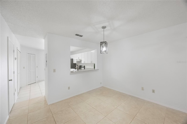 interior space featuring sink, light tile patterned flooring, and a textured ceiling