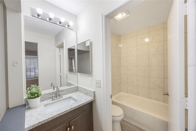 full bathroom featuring vanity, toilet, tiled shower / bath, and a textured ceiling