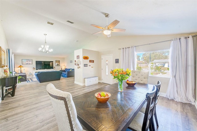 dining area featuring lofted ceiling, ceiling fan with notable chandelier, and light hardwood / wood-style flooring