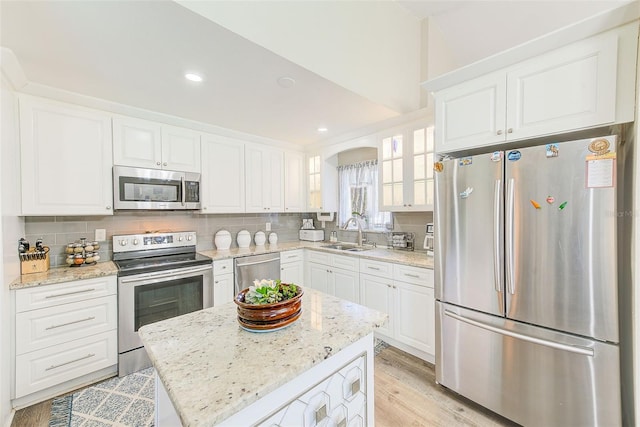 kitchen with stainless steel appliances, light stone countertops, sink, and white cabinets