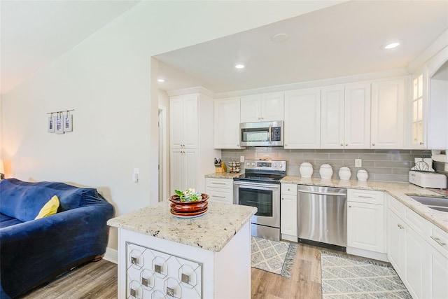 kitchen with stainless steel appliances, a center island, white cabinets, and light wood-type flooring