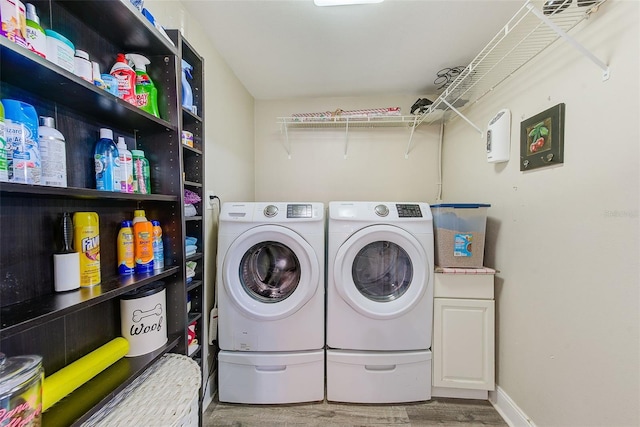 laundry area featuring washer and dryer, wood-type flooring, and cabinets