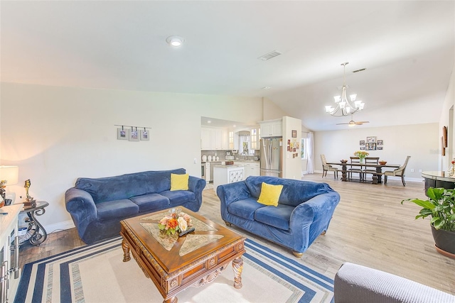 living room featuring lofted ceiling, sink, light hardwood / wood-style floors, and a notable chandelier