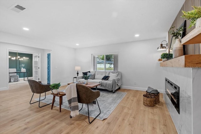 living room featuring a tiled fireplace, light hardwood / wood-style flooring, and a notable chandelier