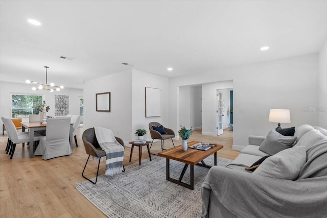 living room with light hardwood / wood-style floors and an inviting chandelier