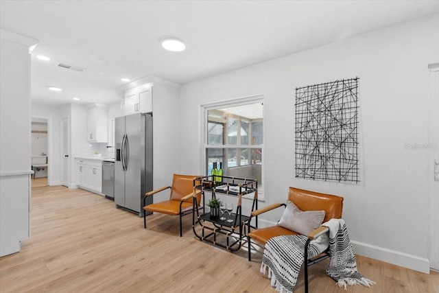 kitchen with stainless steel appliances, white cabinetry, light wood-type flooring, and tasteful backsplash