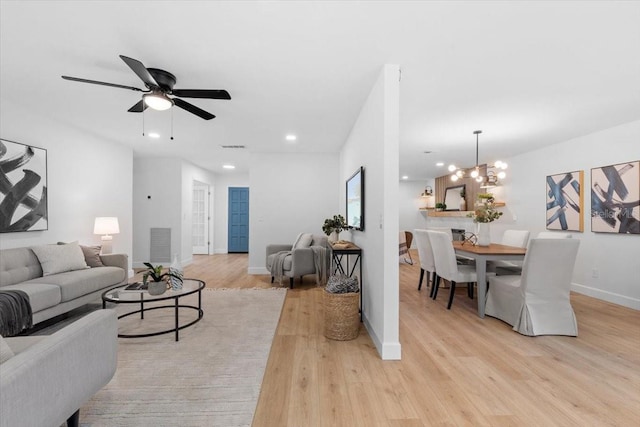 living room with light hardwood / wood-style flooring and ceiling fan with notable chandelier