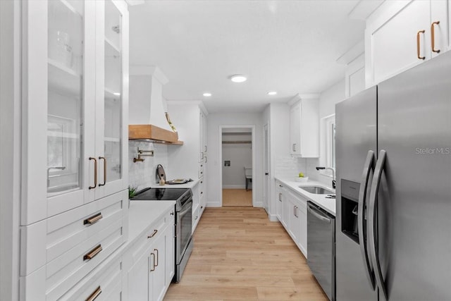 kitchen featuring stainless steel appliances, premium range hood, sink, white cabinetry, and tasteful backsplash