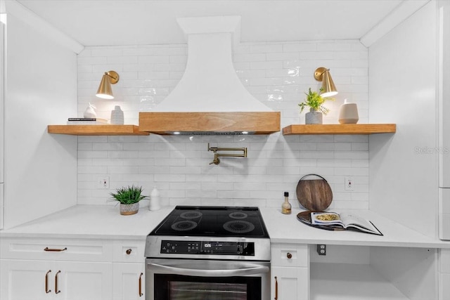 kitchen with premium range hood, white cabinetry, tasteful backsplash, and stainless steel electric range oven