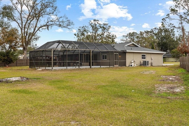 rear view of house featuring central AC, glass enclosure, and a lawn