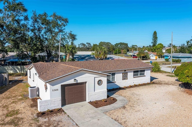 ranch-style house with central air condition unit and a garage