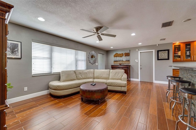 living room with hardwood / wood-style floors, a textured ceiling, and ceiling fan