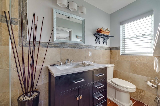 bathroom featuring toilet, vanity, and tile walls