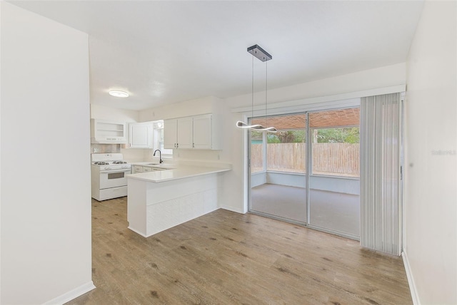 kitchen with white cabinetry, light hardwood / wood-style floors, hanging light fixtures, kitchen peninsula, and white range with gas stovetop