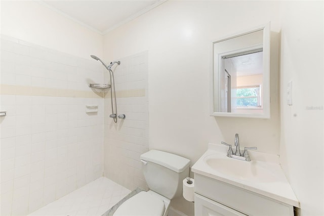 bathroom featuring toilet, ornamental molding, a tile shower, and vanity