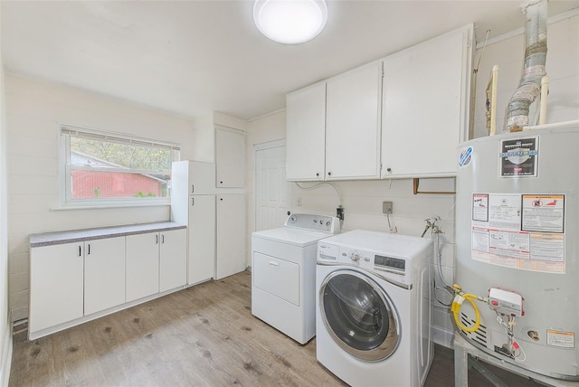 laundry room with water heater, cabinets, washing machine and dryer, and light hardwood / wood-style flooring