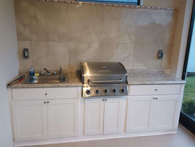 kitchen with tile walls, white cabinetry, and sink