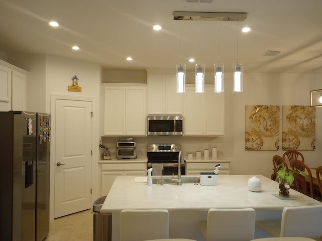 621 San Augusto Dr, Poinciana, FL 34759 - kitchen featuring light countertops, decorative light fixtures, a center island with sink, appliances with stainless steel finishes, and white cabinetry