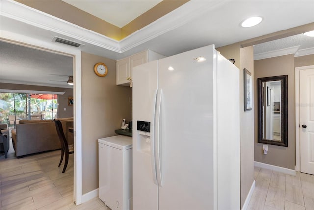 kitchen with ceiling fan, white fridge with ice dispenser, and crown molding