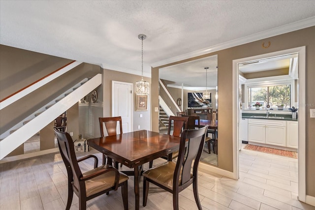 dining space featuring sink, a chandelier, ornamental molding, and a textured ceiling