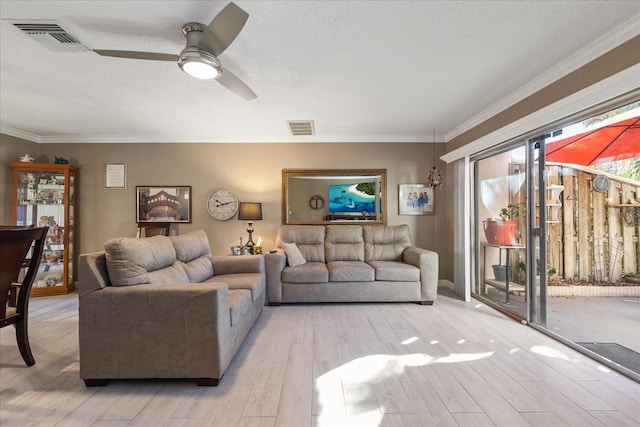 living room with ceiling fan, light wood-type flooring, ornamental molding, and a textured ceiling