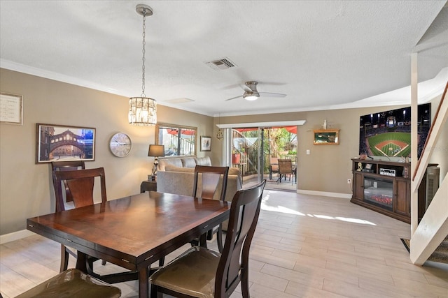 dining area featuring ceiling fan with notable chandelier, a textured ceiling, and crown molding