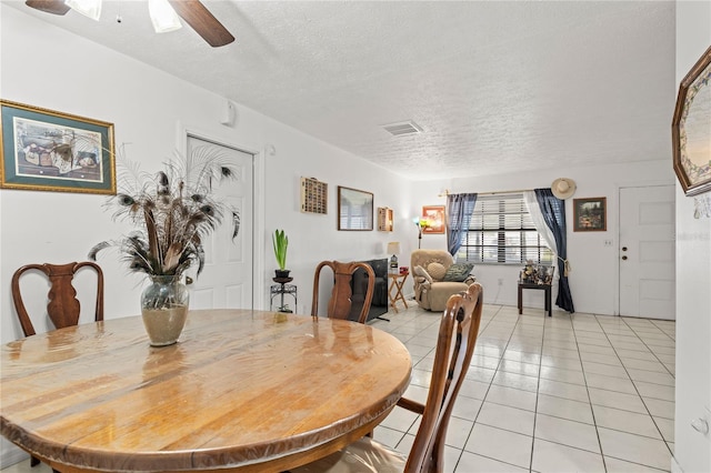 dining space with a textured ceiling, ceiling fan, and light tile patterned floors