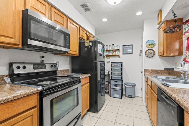 kitchen featuring light stone counters, a textured ceiling, black appliances, light tile patterned flooring, and sink