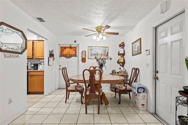 dining room with a textured ceiling, ceiling fan, and light tile patterned floors