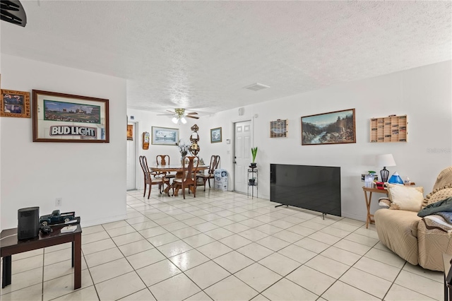 living room featuring a textured ceiling, ceiling fan, and light tile patterned floors