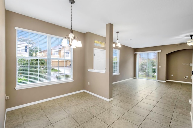 tiled empty room with ceiling fan with notable chandelier and a wealth of natural light