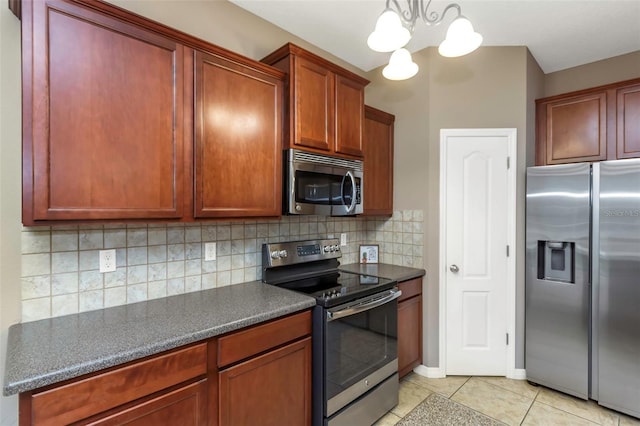 kitchen featuring decorative backsplash, an inviting chandelier, hanging light fixtures, appliances with stainless steel finishes, and light tile patterned floors