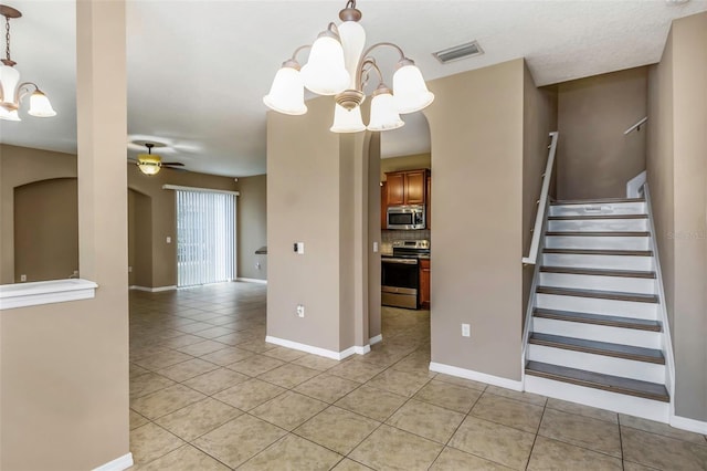 interior space featuring light tile patterned flooring and ceiling fan with notable chandelier