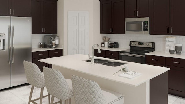 kitchen featuring stainless steel appliances, decorative backsplash, a kitchen island with sink, a breakfast bar area, and sink