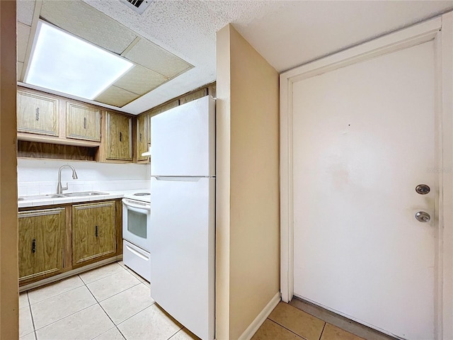 kitchen featuring sink, white appliances, and light tile patterned flooring