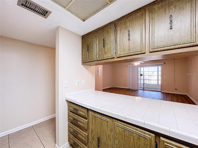 kitchen with light tile patterned floors, ceiling fan, and tile counters