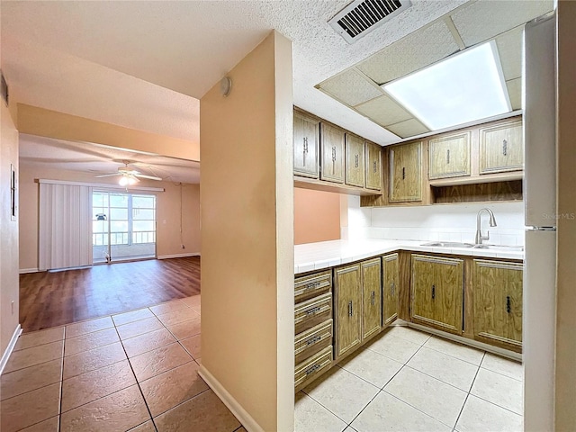 kitchen featuring ceiling fan, sink, light tile patterned floors, and tile countertops