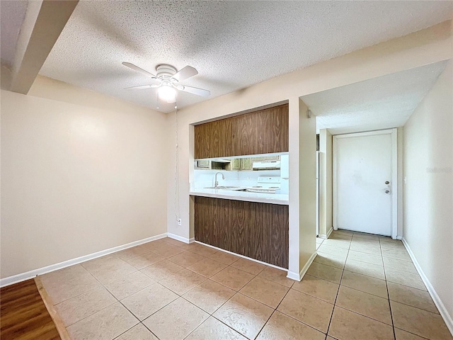 kitchen featuring ceiling fan, sink, electric stove, and light tile patterned floors