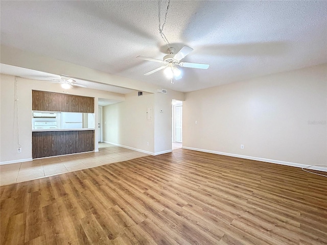 unfurnished living room with a textured ceiling, light hardwood / wood-style flooring, and ceiling fan