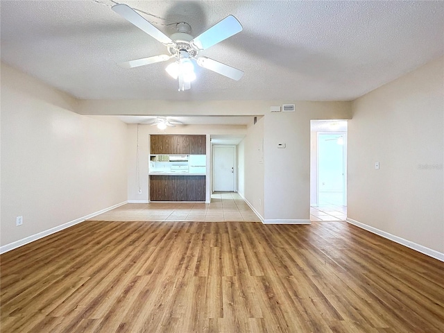 unfurnished living room featuring a textured ceiling, light hardwood / wood-style flooring, and ceiling fan