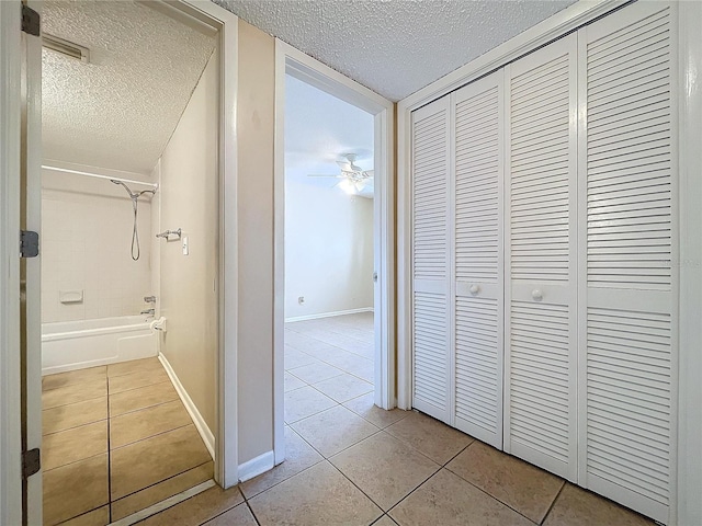 corridor featuring a textured ceiling and light tile patterned floors