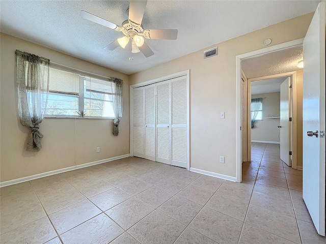 unfurnished bedroom featuring ceiling fan, a textured ceiling, light tile patterned floors, and a closet