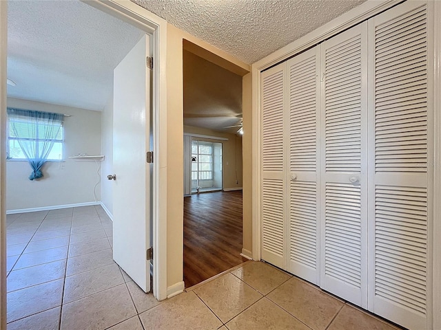 hall featuring a textured ceiling and light tile patterned floors