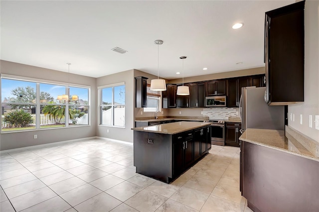 kitchen featuring a notable chandelier, a kitchen island, light tile patterned flooring, hanging light fixtures, and stainless steel appliances