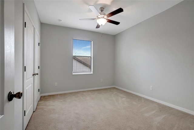 spare room with ceiling fan and light carpet